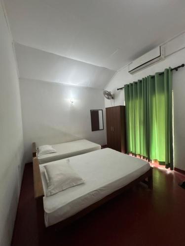 een slaapkamer met 2 bedden en groene gordijnen bij Nimsara Holiday Resort in Anuradhapura