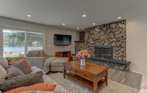 a living room with a stone fireplace and a table at Welk Manor Private Waterfront Retreat on the Spokane River in Post Falls