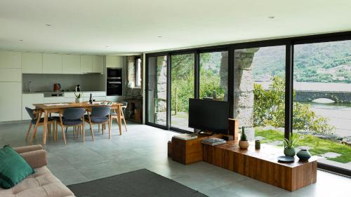 a living room with a television and a table with chairs at Casas de Pousadouro in Baião