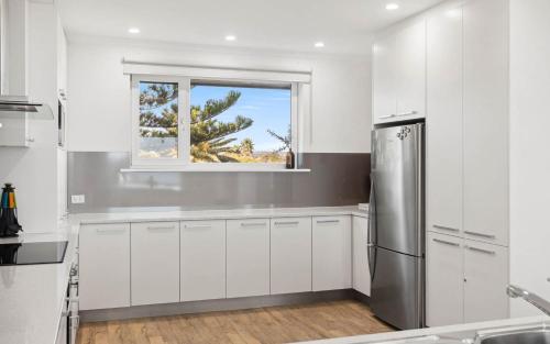 a kitchen with white cabinets and a window at 35 Degrees South in Port Noarlunga