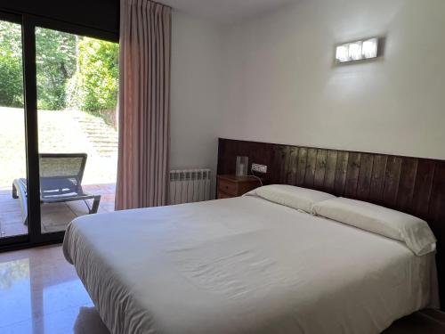 a bedroom with a large bed and a sliding glass door at Cal Cisteller in Santa Pau