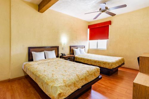 a hotel room with two beds and a ceiling fan at Capital O Hotel Del Parque Guadalajara in Guadalajara