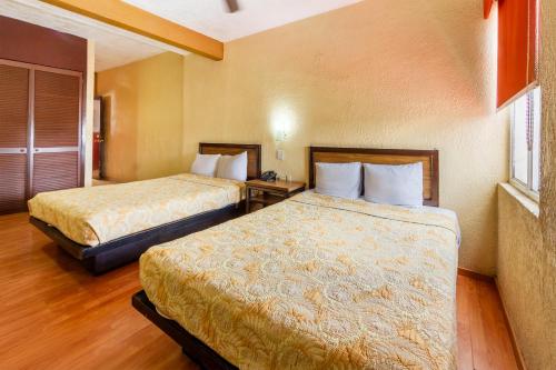 a hotel room with two beds and a window at Capital O Hotel Del Parque Guadalajara in Guadalajara