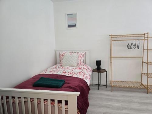 a white bedroom with a bed with a red blanket at Grace's Place in Littleport in Littleport