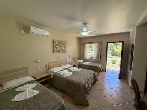 a hotel room with two beds and a window at Ózera Hotel Fazenda in Prudentópolis