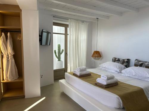 a white bedroom with a bed and a window at ANDELIAS Signature Suites in Chora Folegandros