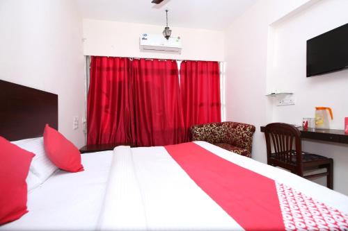 a bedroom with a large bed with a red curtain at Hotel O Dwarika Inn in Jabalpur