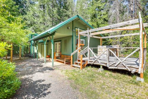 a green house with a porch and a fence at Spring-Fed Soaking Tub! Lush Central Oregon Haven in McKenzie Bridge
