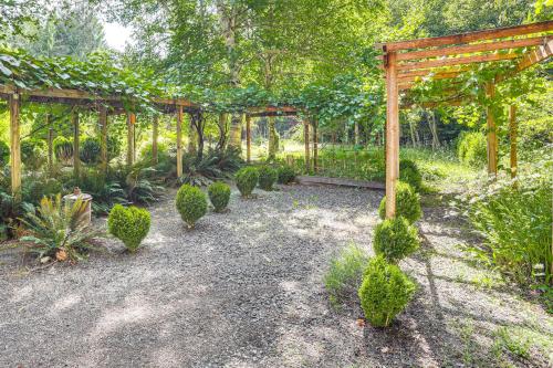 a garden with a wooden pergola and green plants at Spring-Fed Soaking Tub! Lush Central Oregon Haven in McKenzie Bridge