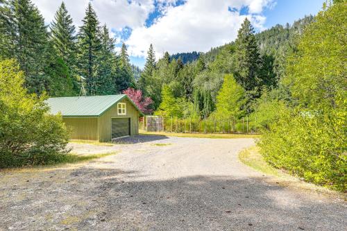 a gravel road leading to a green building in the woods at Spring-Fed Soaking Tub! Lush Central Oregon Haven in McKenzie Bridge