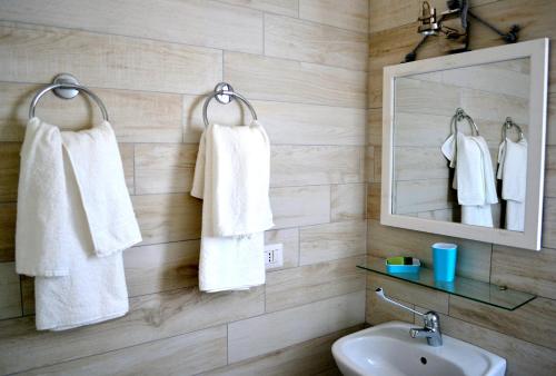 a bathroom with white towels hanging on a wall at B&B La Casa Bianca di Porto Conte in Porto Conte