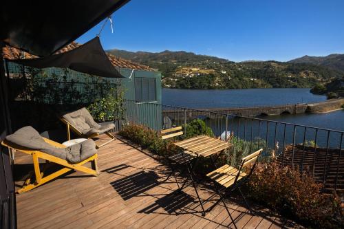 a deck with chairs and a table with a view of a lake at Casas de Pousadouro in Baião