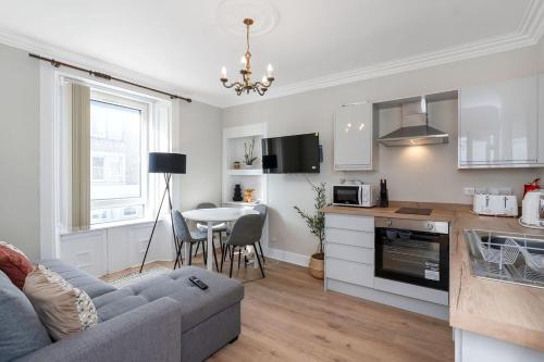 a living room and kitchen with a couch and a table at Vacant Nest Central Location Wifi & Shops in Hawick