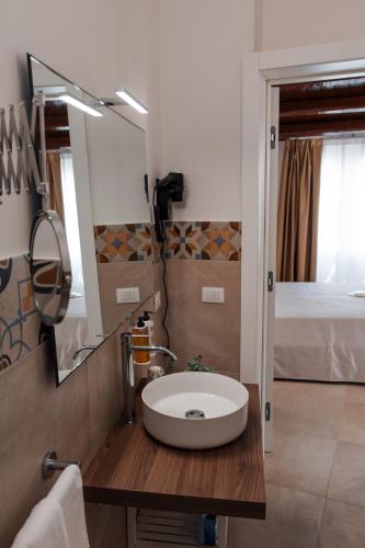 a bathroom with a sink and a mirror and a bed at Vacanze da Beppuccio Scoglitti in Vittoria