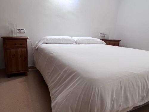 a bedroom with a white bed and two night stands at Cal Cisteller in Santa Pau