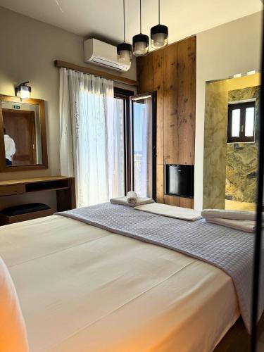 a bedroom with a large white bed with a tv at Armenopetra View Gerolimenas in Gerolimenas