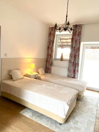 two beds in a room with two windows at Hanna Vendégház-Tállya in Tállya