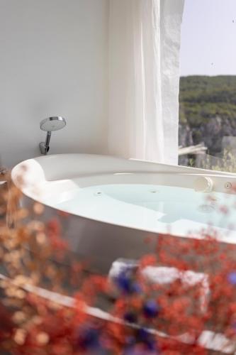 a bath tub in a room with a window at Hacienda Na Xamena, Ibiza in Na Xamena