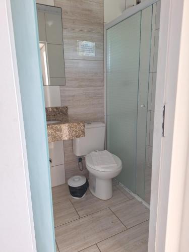 a bathroom with a toilet and a glass shower at Coração Do Oceano Village in Penha