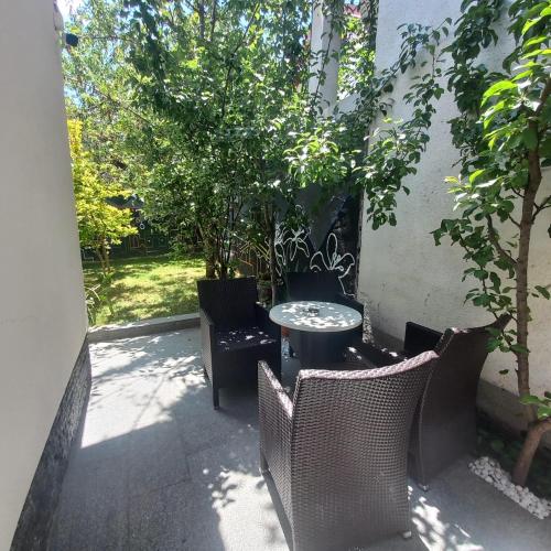 a patio with a table and chairs and trees at APARTMENTS NENSI in Sarajevo