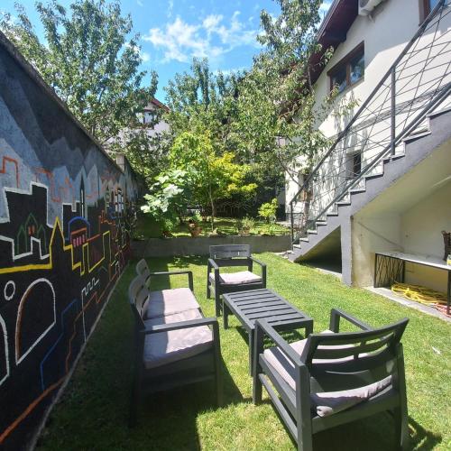 three benches sitting in the grass next to a wall at APARTMENTS NENSI in Sarajevo