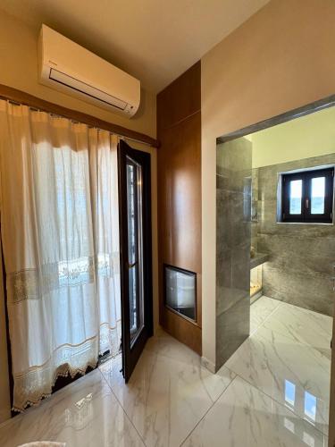 a bathroom with a shower and a television and a window at Armenopetra View Gerolimenas in Gerolimenas