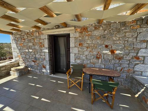 a patio with a table and chairs and a stone wall at Armenopetra View Gerolimenas in Gerolimenas