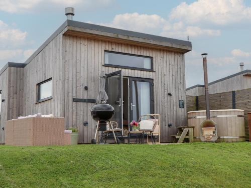 a small wooden house with a grill and chairs at The Bickleigh in Tiverton