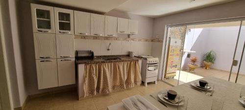 a kitchen with white cabinets and a table in it at Rota dos Vinhedos in Espirito Santo Do Pinhal