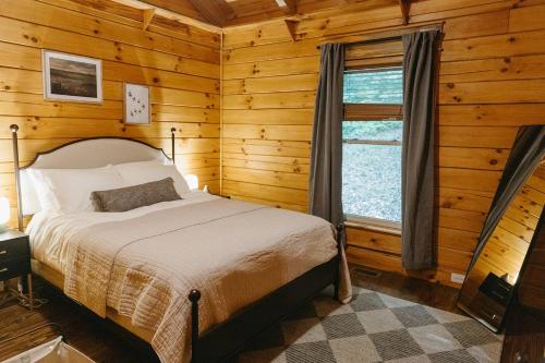 ein Schlafzimmer mit einem Bett in einer Blockhütte in der Unterkunft "Alpine Hills" Cozy Hideaway RRG Cabin w/ Hot Tub in Stanton