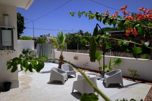 a courtyard with white chairs and flowers on a wall at Vacanze da Beppuccio Scoglitti in Vittoria