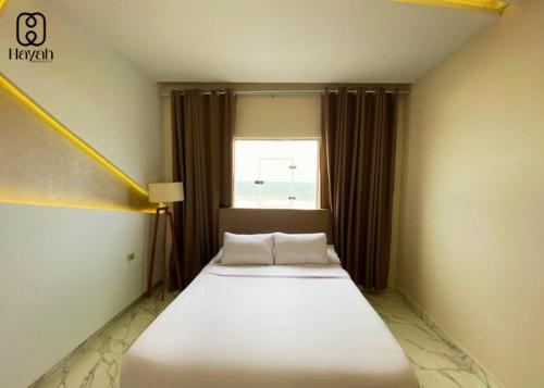 a white bed in a room with a window at Hayah Waterfalls Hotels in Alexandria