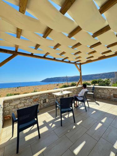 a person sitting on a patio with a table and chairs at Armenopetra View Gerolimenas in Gerolimenas