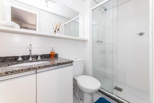 a white bathroom with a toilet and a shower at Green Center - Centro de Curitiba - 1 quarto in Curitiba