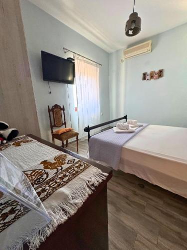 a room with two beds and a chair and a television at Armenopetra View Gerolimenas in Gerolimenas
