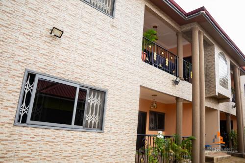 a brick building with a window and a balcony at ReneGhart Apartments in Kasoa
