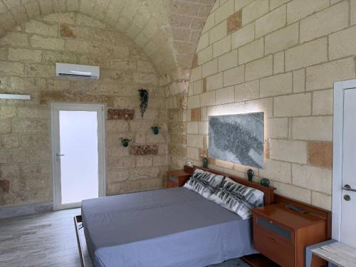 a bedroom with a bed in a stone wall at Largo Spani 15 in Veglie