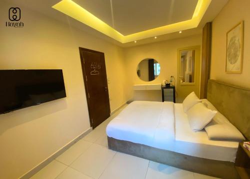 a bedroom with a large white bed and a tv at Hayah Waterfalls Hotels in Alexandria