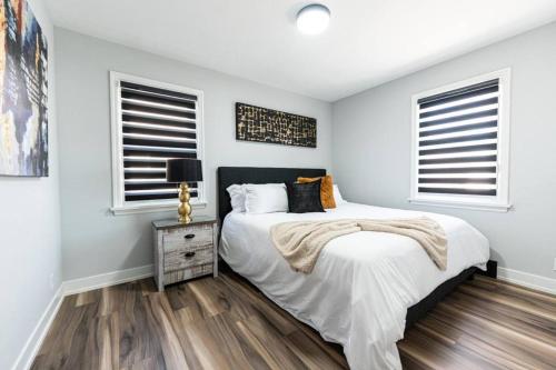 a bedroom with a bed and two windows at Outdoor Sauna Hot Tub Playroom Port Dallhousie in St. Catharines