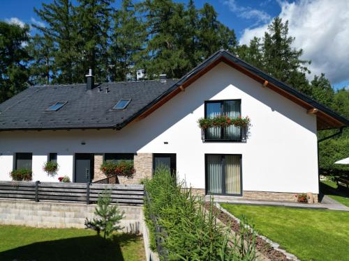 a white house with a black roof at Apartmány Runi in Stará Lesná