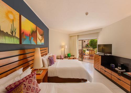 a hotel room with a bed and a television at Grand Decameron Los Cabos, A Trademark All-Inclusive Resort in San José del Cabo