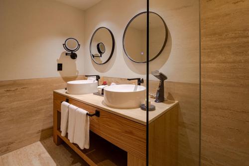 a bathroom with two sinks and two mirrors at Camino Real Polanco Mexico in Mexico City
