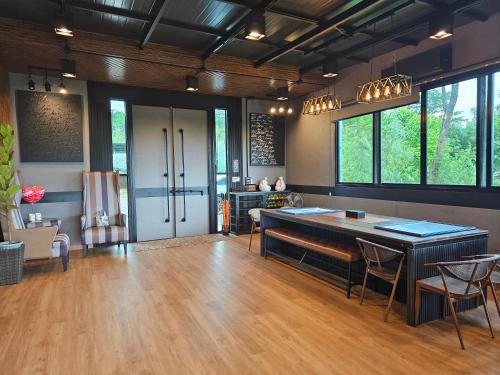 a living room with a table and chairs and windows at Black Sheep House Khaoyai by ALPHATEL PARTNER in Pong Talong