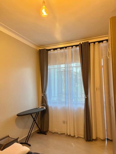 a room with a window with curtains and a table at Vibe Apartments in Kampala