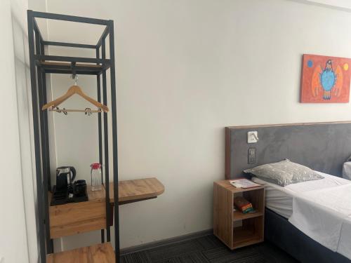 a bedroom with a bed and a wooden night stand at Osh Art Hotel in Osh