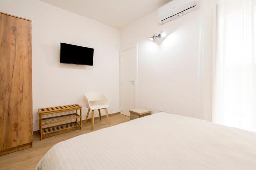 a white bedroom with a bed and a tv at NonnaLo' bed and breakfast in Verbicaro