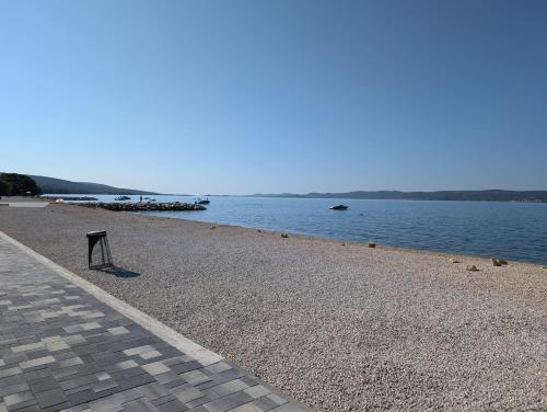 a beach with a bench next to the water at Apartment Como Sukosan , 30m vom Meer in Sukošan
