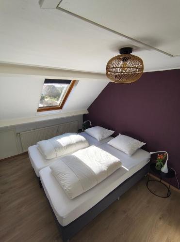 a bedroom with a large bed with white sheets and pillows at BijOpaenOma in Oosterend