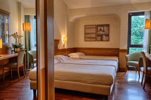 a bedroom with two beds and a table and chairs at BV Grand Hotel Assisi in Assisi