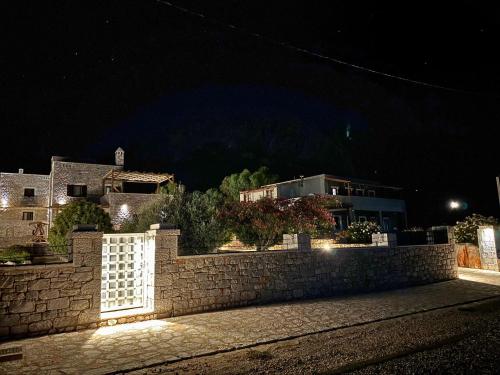 a stone fence in front of a house at night at Armenopetra View Gerolimenas in Gerolimenas